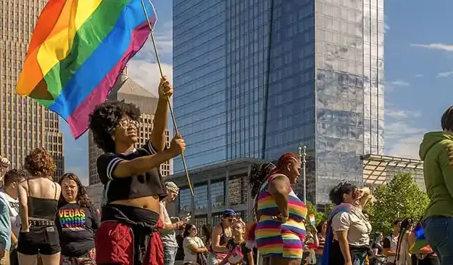 people in a crowd wearing rainbow colors and waving a rainbow flag